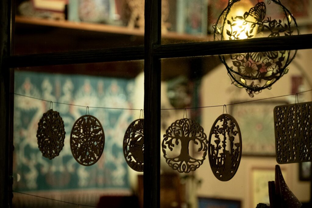 Ornate cutouts hang on a string in a window.